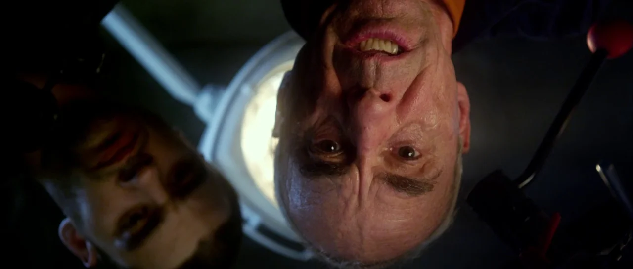 Universal Soldier: Day of Reckoning (2012) movie still: closeup — A dimly lit room features a large overhead surgical lamp illuminating two men. The…