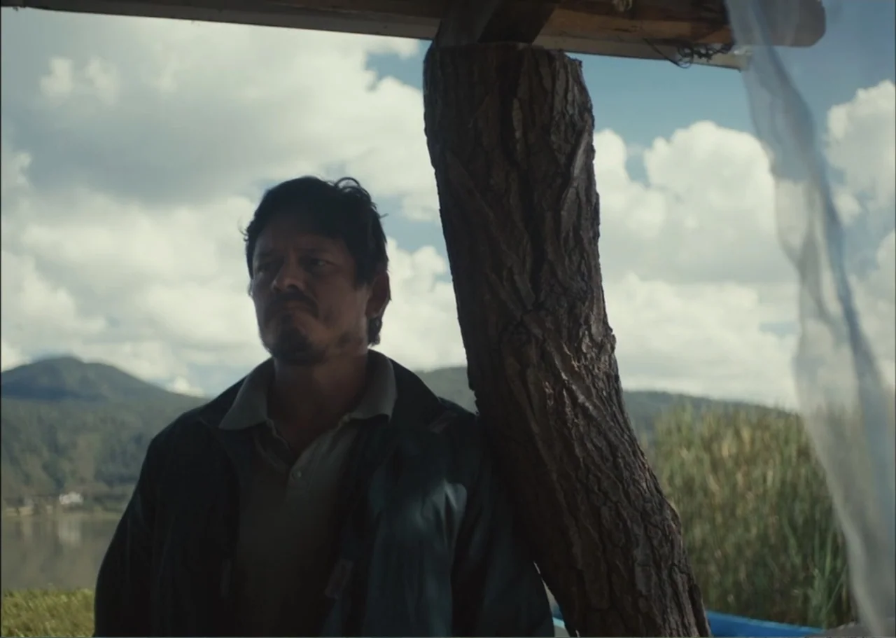 A Fisherman's Tale (1976) movie still: medium — A lakeside exterior features a wooden structure overlooking distant mountains and water. A man in a…