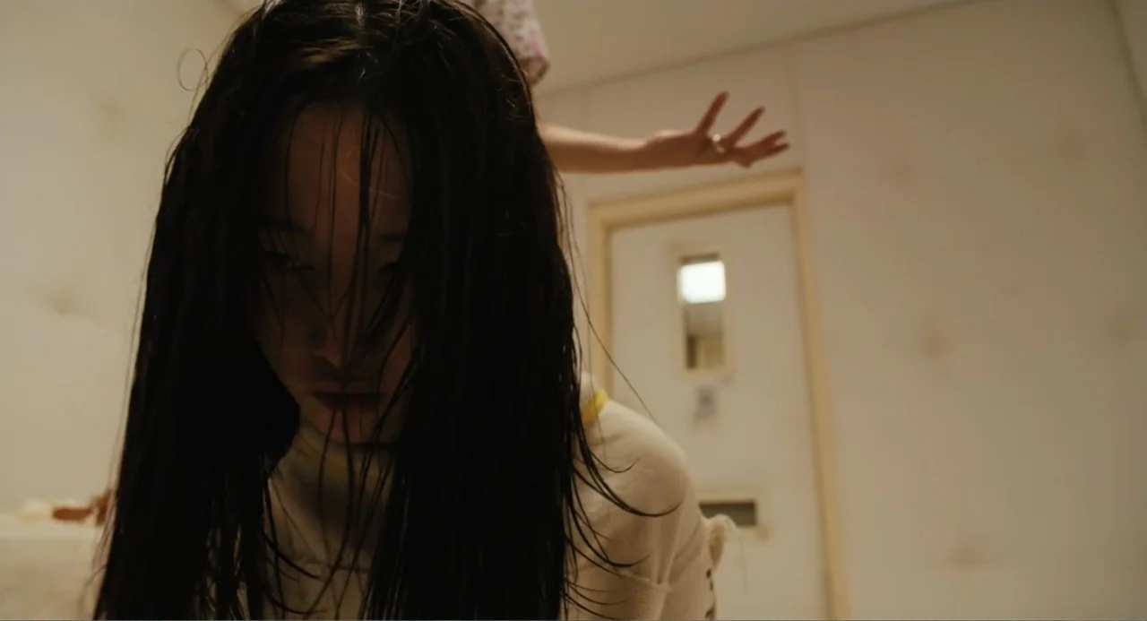 Mona Lisa and the Blood Moon (2022) movie still: closeup — A stark white room with padded walls features a closed door with a small window. A person…