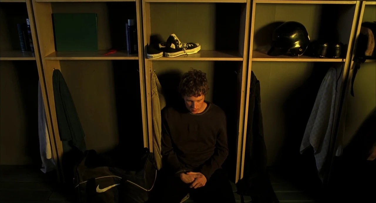 A History of Violence (2005) movie still: medium — A rows of wooden cubicles features personal items and hanging towels in an athletic locker room.…