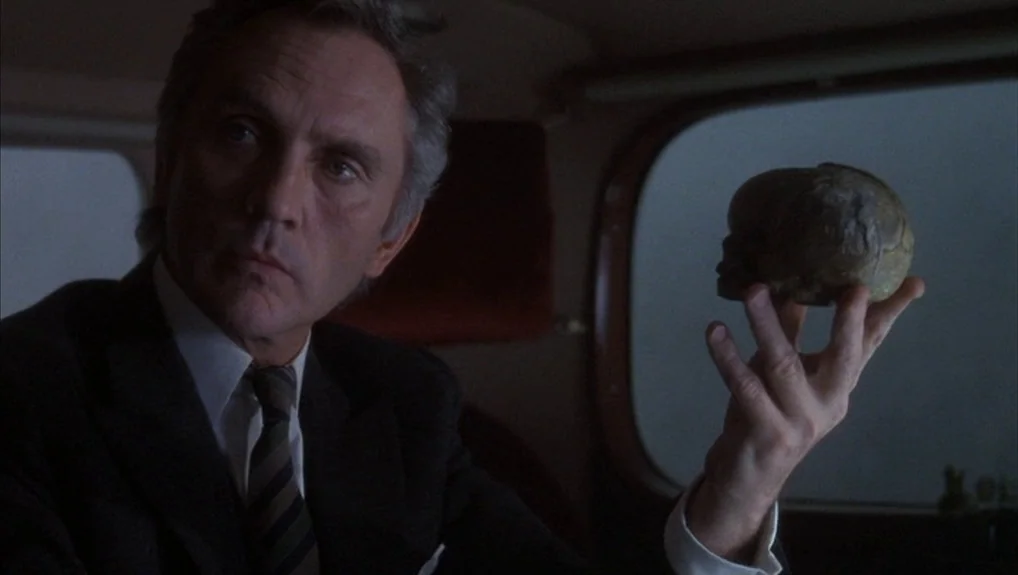 The Company of Wolves (1984) movie still: medium — An interior of a vehicle with a dark upholstered seat and foggy windows. A man sits in the…