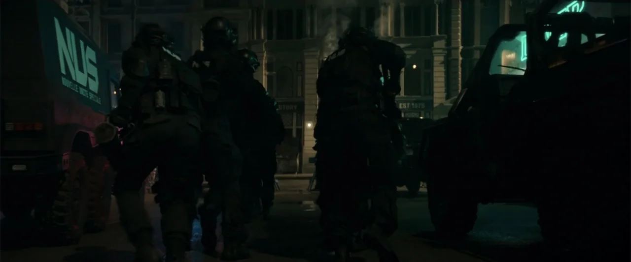 McWalter (2025) movie still: fullbody — A dark city street at night features armored vehicles parked on the sides. Several tactical soldiers in…
