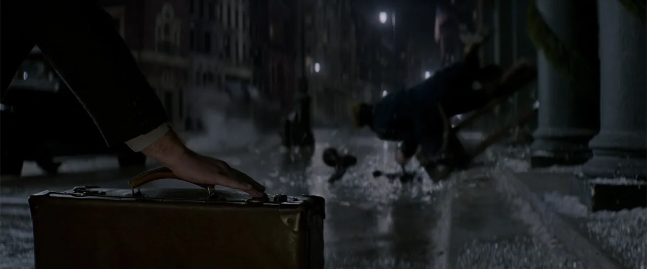Fantastic Beasts and Where to Find Them (2016) movie still: medium — A dark city street at night features wet pavement and scattered debris. A…
