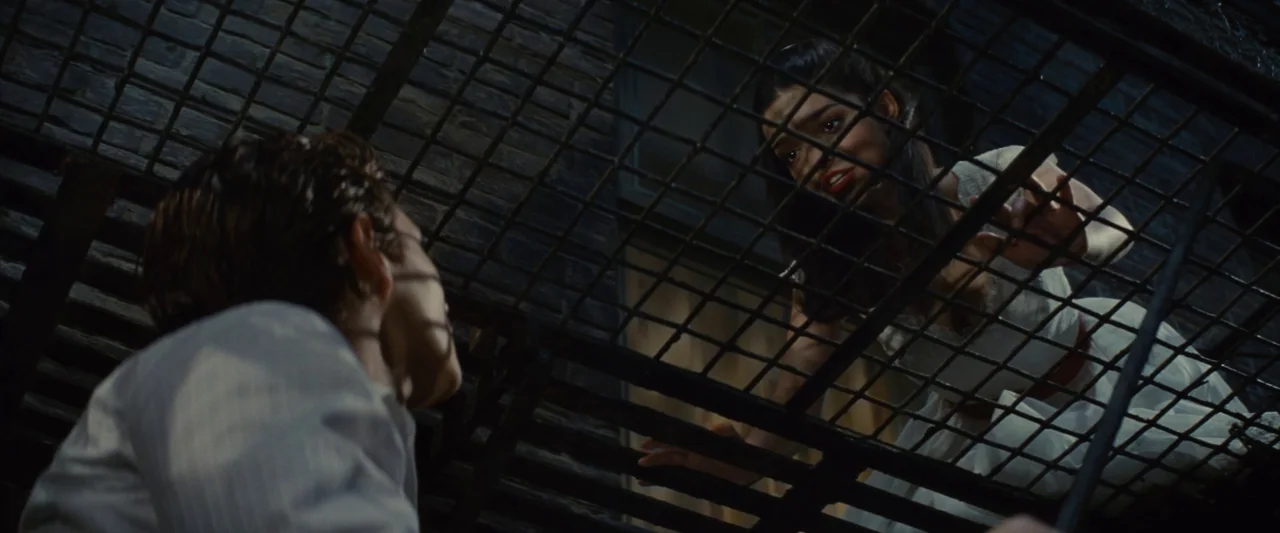 Making of: West Side Story (2021) movie still: medium — A dark urban fire escape with brick walls and metal stairs at night. A woman gazes down from…