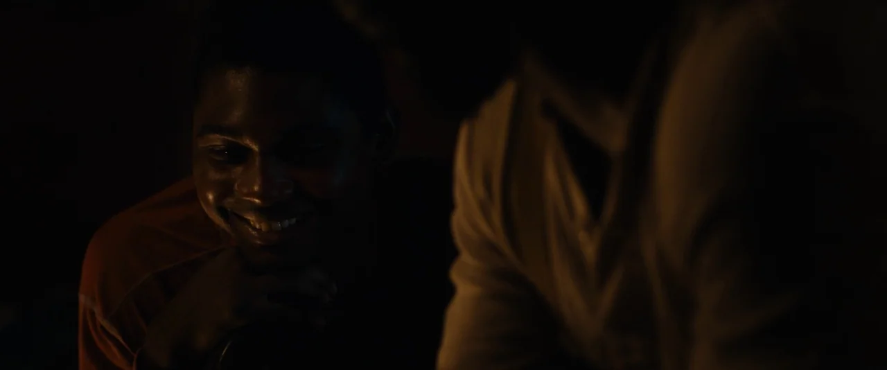 Mudbound (2017) movie still: medium — A dark, dimly lit environment where only the faces of two men are visible. One man smiles at an unseen object…