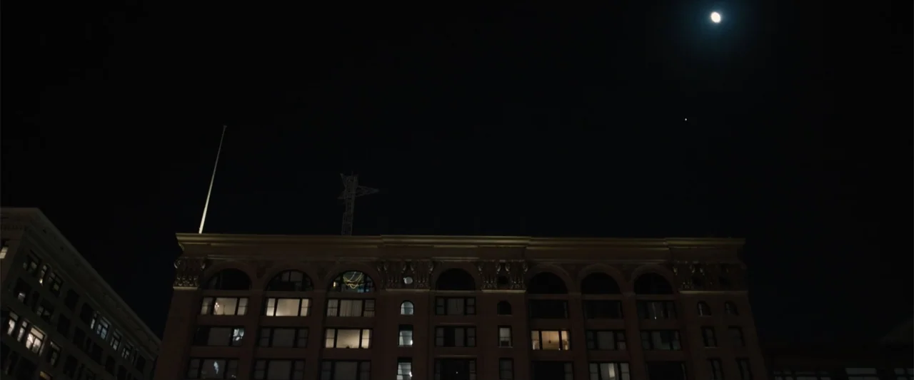 Equation of Love and Tone Deafness (2015) movie still: establishing — A multi-story historic brick building with arched window details is…