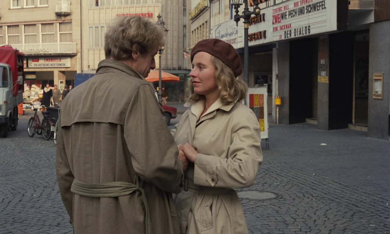 Wrong Move (1975) movie still: medium — A cobble-stoned public square features a cinema marquee in the background advertising films. A man and a…