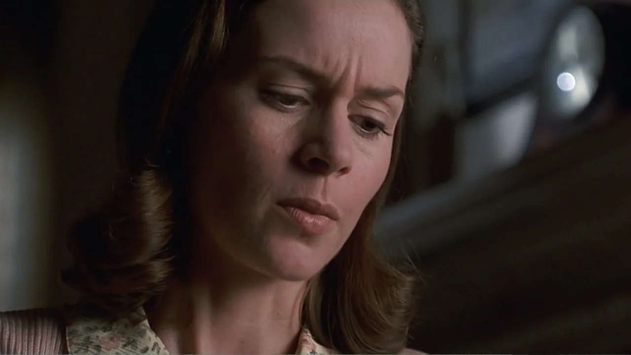 Matilda (1996) movie still: closeup — A dimly lit room provides the backdrop for the close-up shot. A woman looks downward with a subtle furrow in…