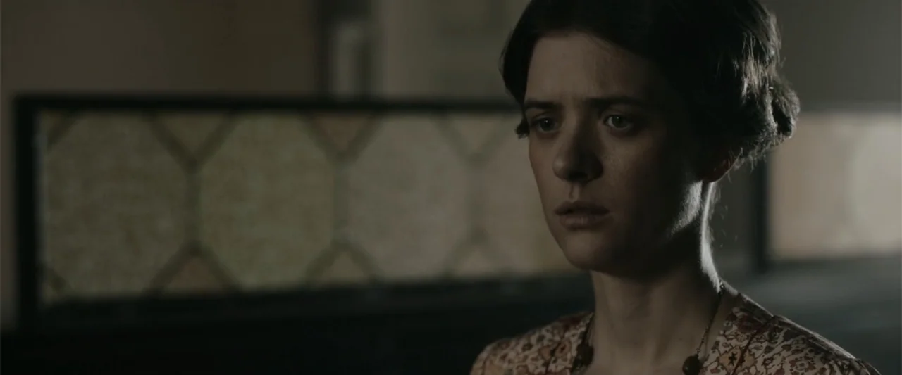 Freud's Last Session (2023) movie still: closeup — An interior space features a dark patterned decorative screen in the background. A woman in a…