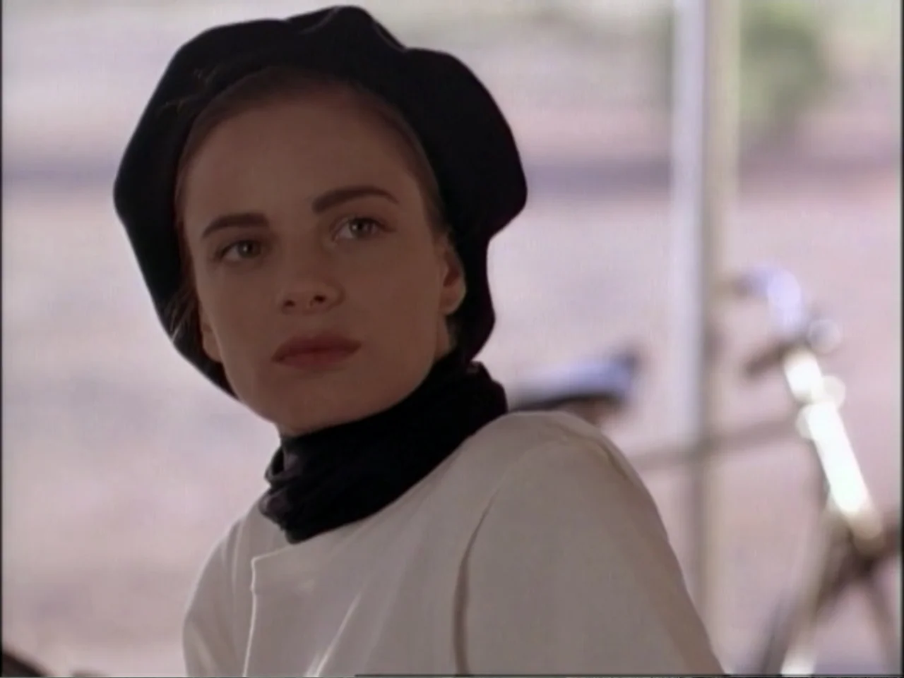 In Pursuit of Honor (1995) movie still: closeup — A woman wears a black beret outdoors in an open, bright environment. She turns her head to look…