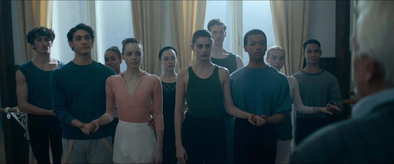 Birds of Paradise (2021) movie still: medium — A group of young dancers stands in a bright room with tall windows and curtains. They are arranged in…