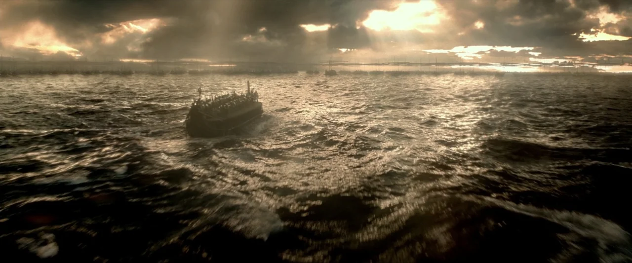 300: Rise of an Empire (2014) movie still: wide — A dark, choppy sea spans the frame under a dramatic, cloud-filled golden sky. A lone, packed…