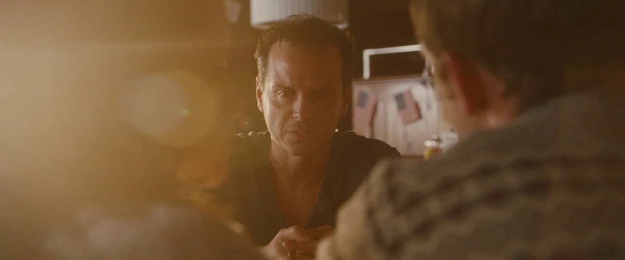 All Of Us Strangers (2023) movie still: medium — A diner booth interior with soft window light creating a bright hazy lens flare. A man faces the…
