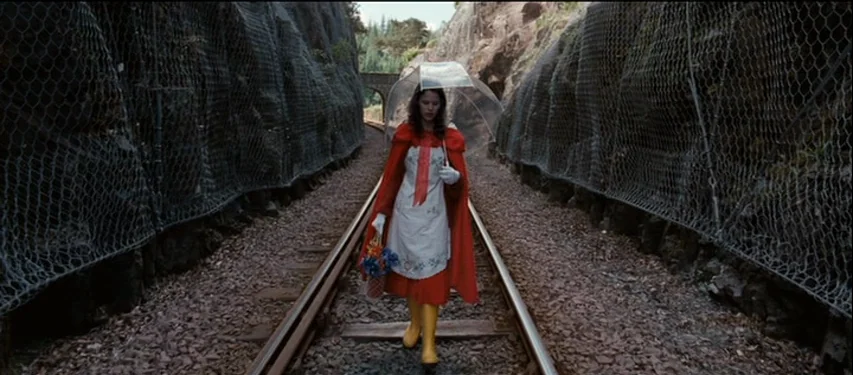 Mister Lonely (2007) movie still: fullbody — A woman walks down a narrow railway track bed enclosed by high rocky walls. The tracks are flanked by…