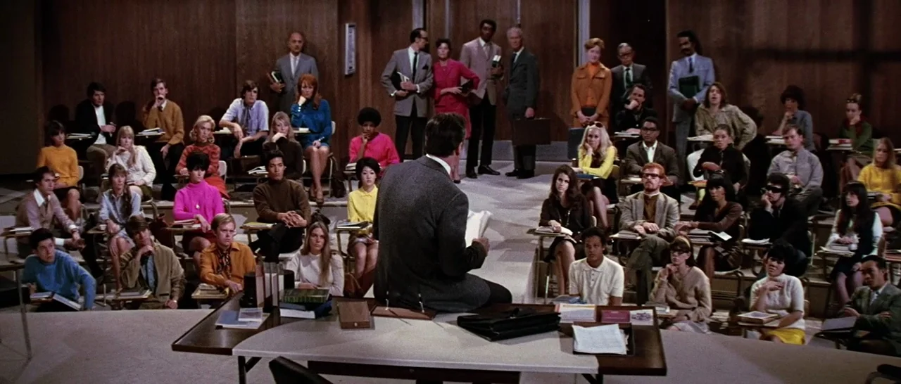 On A Clear Day You Can See Forever (1970) movie still: wide — A crowded university lecture hall features rows of students sitting at individual…