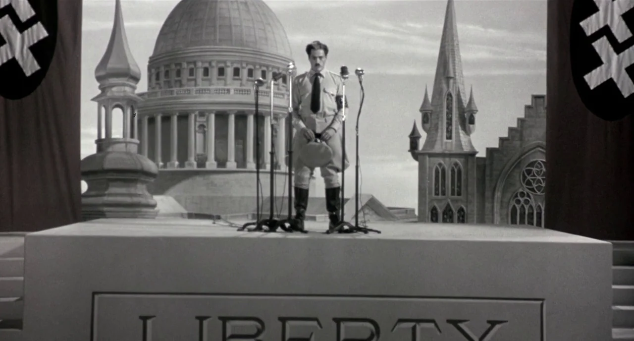 Chaplin (1992) movie still: wide — A stone podium sits in front of a dome and gothic architecture backdrop. A man in military uniform stands alone…