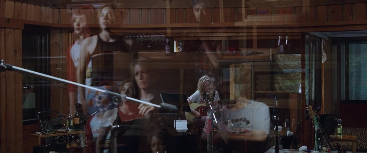 Her Smell (2018) movie still: medium — A wood-paneled recording studio with multiple microphones and instruments visible behind a glass partition.…