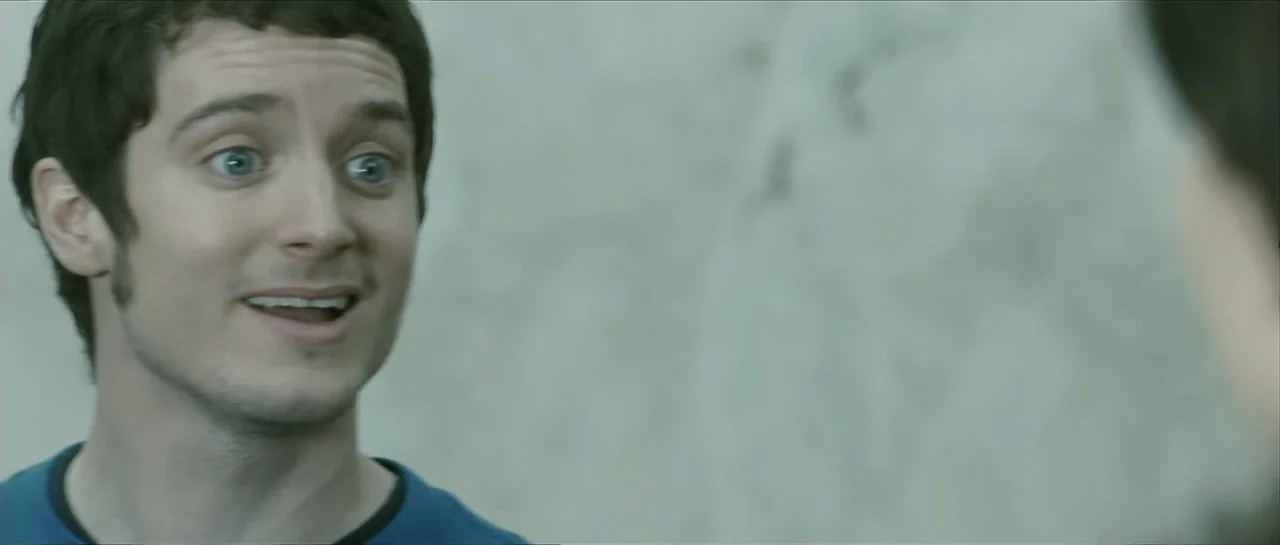 The Oxford Murders (2008) movie still: closeup — A simple interior space with a plain, light-colored wall background. A man with short dark hair is…