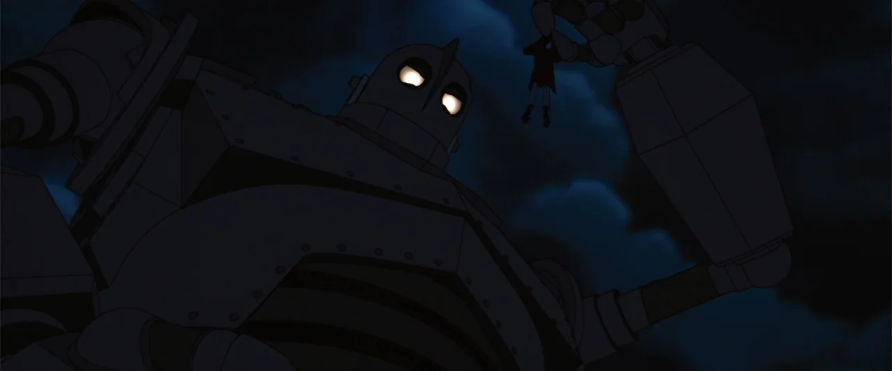 The Iron Giant (1999) movie still: medium — A massive mechanical robot looms against a dark, cloudy nighttime sky. The robot holds a small child in…