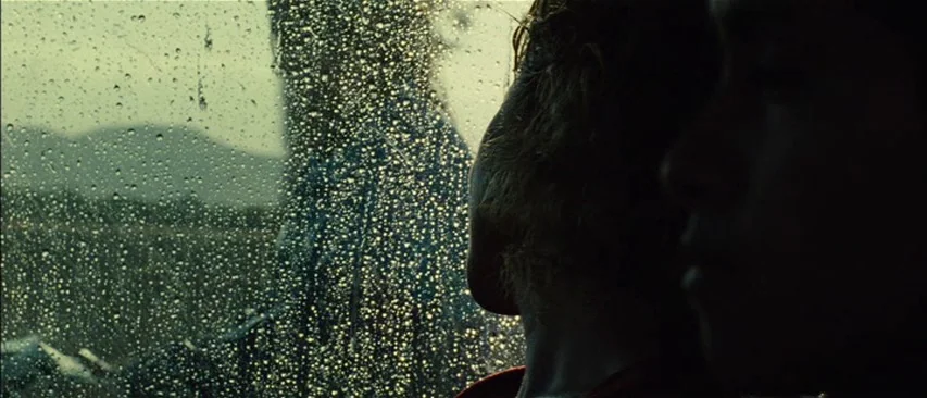 The Headless Woman (2008) movie still: medium — A view from inside a vehicle looking through a rainy glass window at a landscape. Two people sit in…
