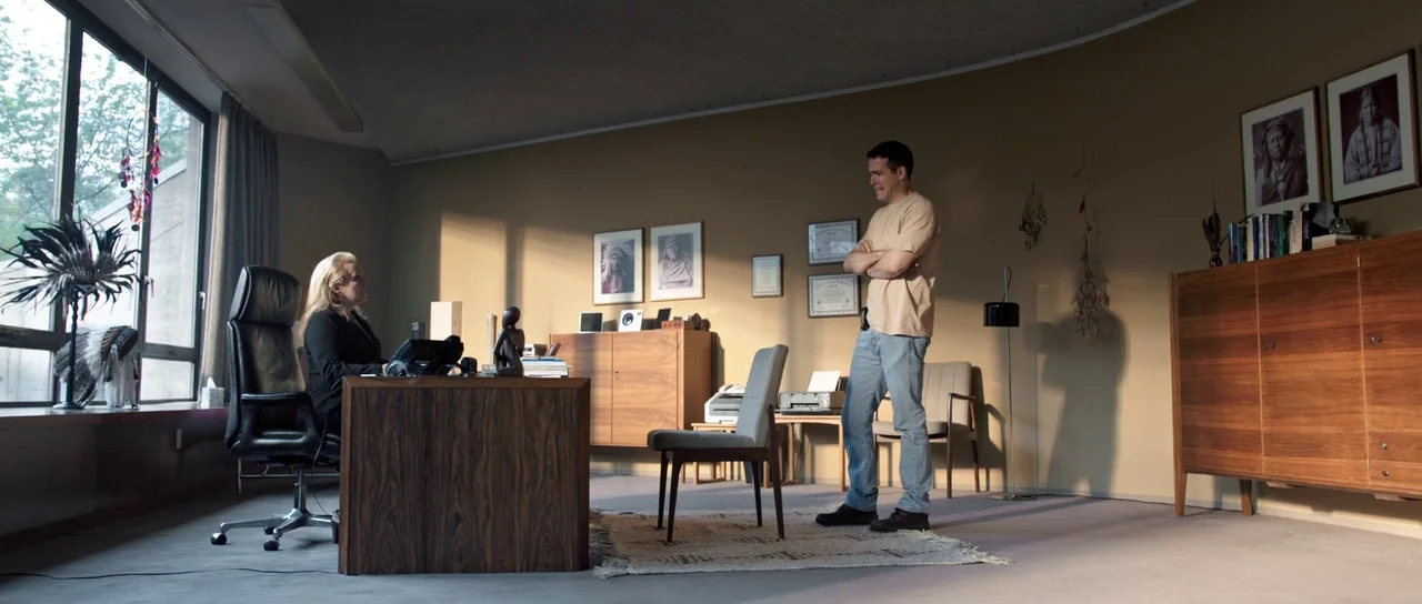 The Voices (2014) movie still: wide — A spacious professional office with warm-toned walls, wooden cabinets, and large floor-to-ceiling windows. A…
