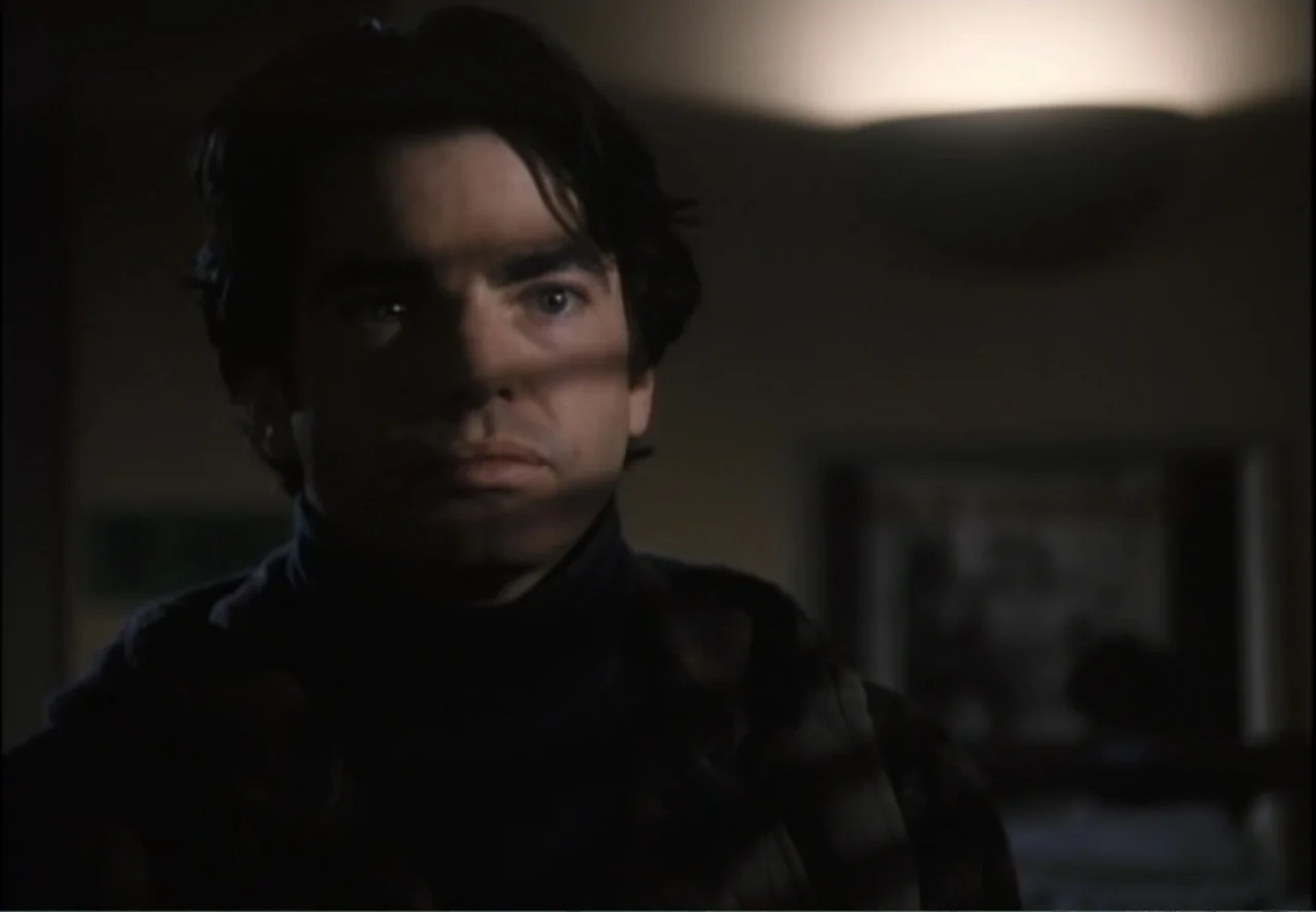 White Mile (1994) movie still: closeup — A dimly lit room features a man with shadows cast across his face. The man stands still while gazing ahead…
