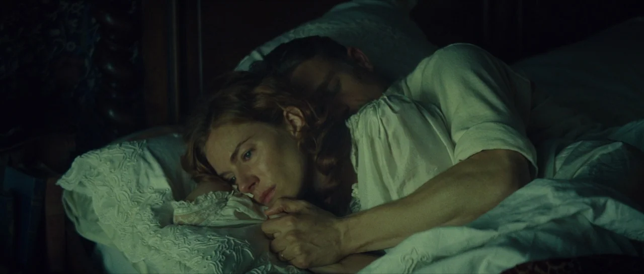 The Lost City of Z (2016) movie still: closeup — A dark bedroom at night features a man and woman lying together in bed. They lie close on white…