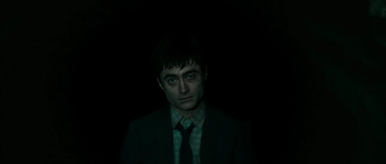 Swiss Army Man (2016) movie still: closeup — A man stands in an environment defined by deep shadows and absolute darkness. He remains stationary…