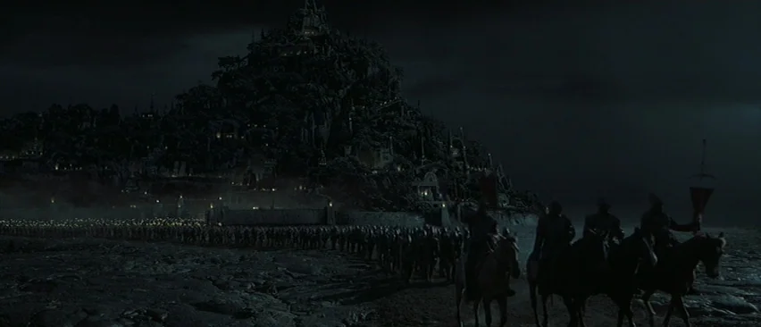 Planet of the Apes (2001) movie still: establishing — A vast, dark, rocky landscape leads to a formidable fortress built into a massive mountain. A…