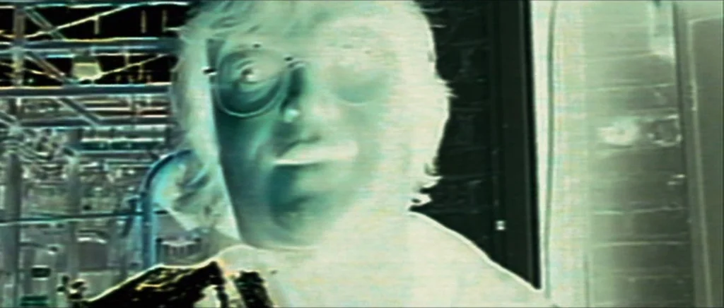 Be Kind Rewind (2008) movie still: closeup — A man stands in an industrial setting with complex pipework and machinery in the background. The image…