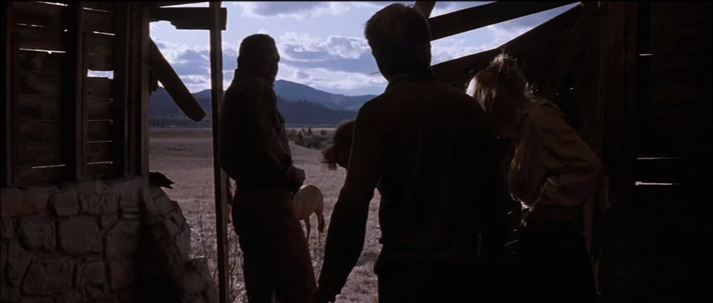 Unforgiven (1992) movie still: medium — An interior of a broken-down wooden structure overlooks a vast grassy plain with hills. Three figures stand…