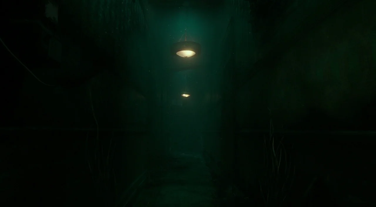 The Shape of Water (2017) movie still: establishing — A dark, narrow corridor filled with a thick teal-tinted atmosphere and submerged features. Two…