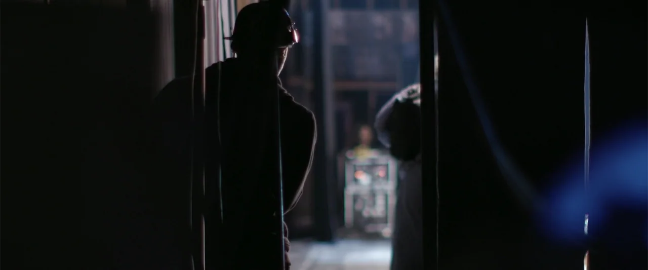 Maxine's Baby: The Tyler Perry Story (2023) movie still: medium — A dark, cramped backstage area with heavy curtains lining the perimeter walls. A…