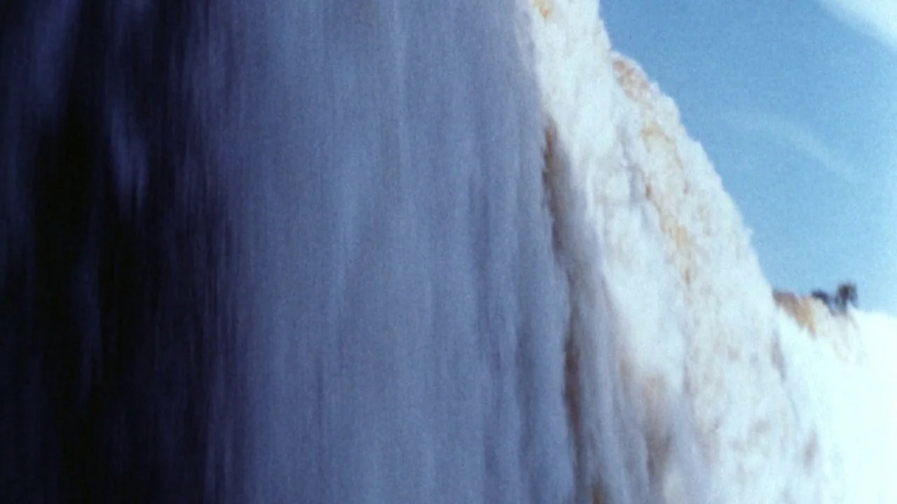 Shock Corridor (1963) movie still: closeup — A close-up view shows a waterfall cascading over a textured white rock cliff. The water falls in a…