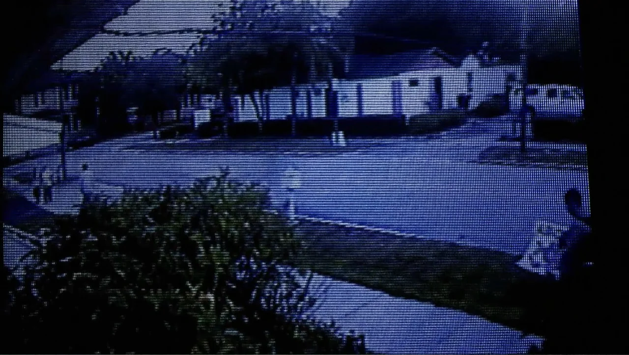 12th & Delaware (2010) movie still: establishing — A quiet residential street at night is captured through a grainy surveillance camera feed. Low…
