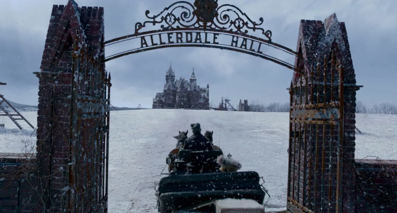 Crimson Peak (2015) movie still: wide — A snowy field features a large, ornate wrought-iron gate labeled Allerdale Hall. A person drives a…