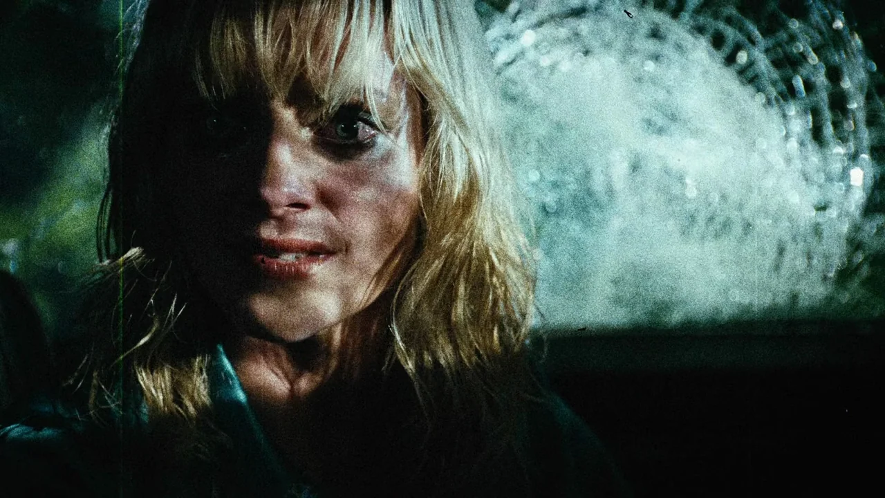 Planet Terror (2007) movie still: closeup — A close-up shot inside a dimly lit car at night with intense shadows. The woman stares forward while the…