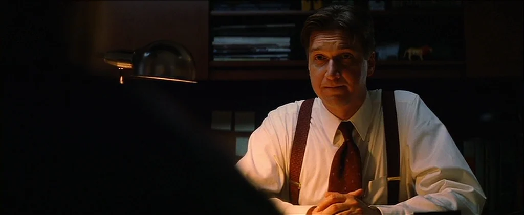 Magnolia (1999) movie still: medium — A dimly lit office features a desk with a lamp and shelves of books. A man in a white dress shirt and…