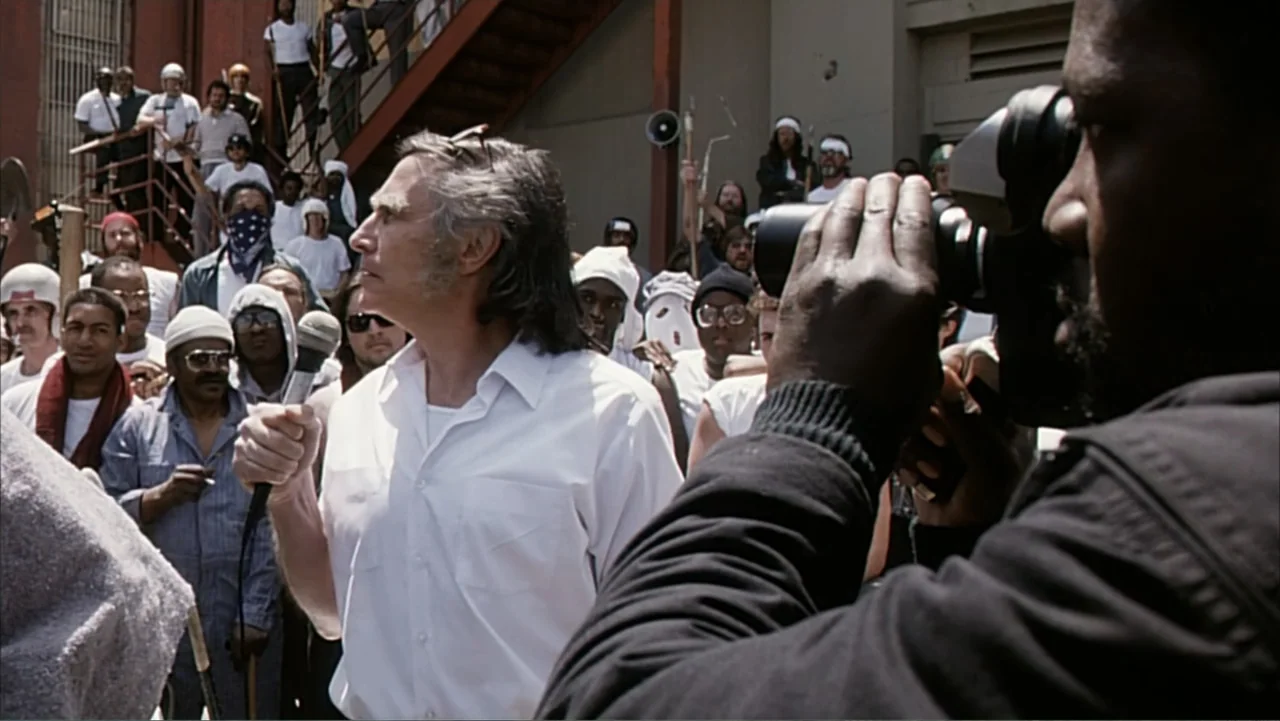 Against the Wall (1994) movie still: medium — A crowded prison yard features many men in white uniforms standing outdoors in daylight. A man in a…