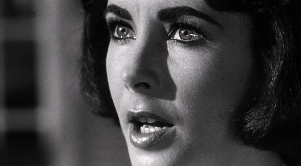 Suddenly, Last Summer (1959) movie still: closeup — A close-up shot of a woman with dark hair in a dim interior. The subject gazes off-camera with…
