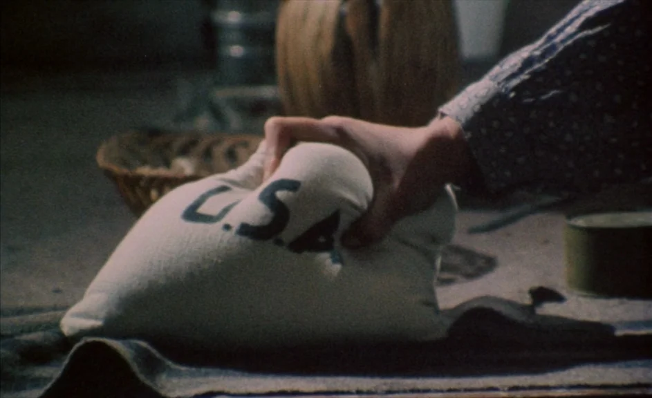 The Kingdom of Naples (1978) movie still: closeup — A dimly lit room holds a collection of rustic supplies and metal containers. A person's hand…