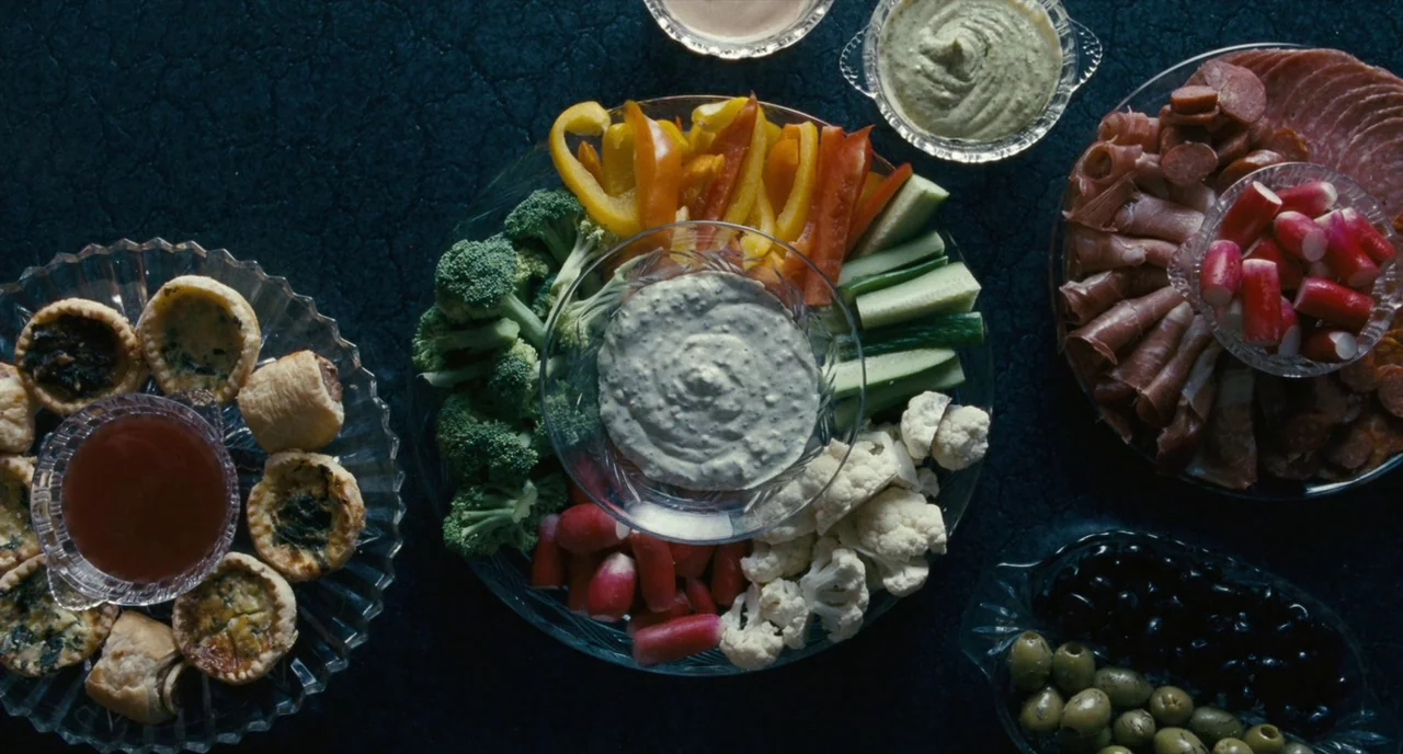 It’s Only The End Of The World (2016) movie still: establishing — Several crystal platters of hors d'oeuvres are arranged on a dark, textured…