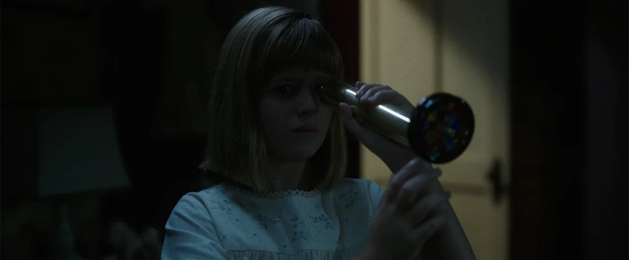 Annabelle: Creation (2017) movie still: medium — A dimly lit room with an out-of-focus doorway visible in the background. A young girl in a white…