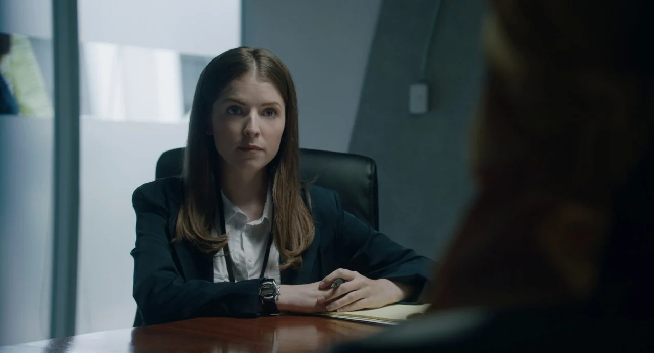 The Day Shall Come (2019) movie still: medium — A modern professional meeting space features frosted glass walls and a dark wood table. A woman sits…