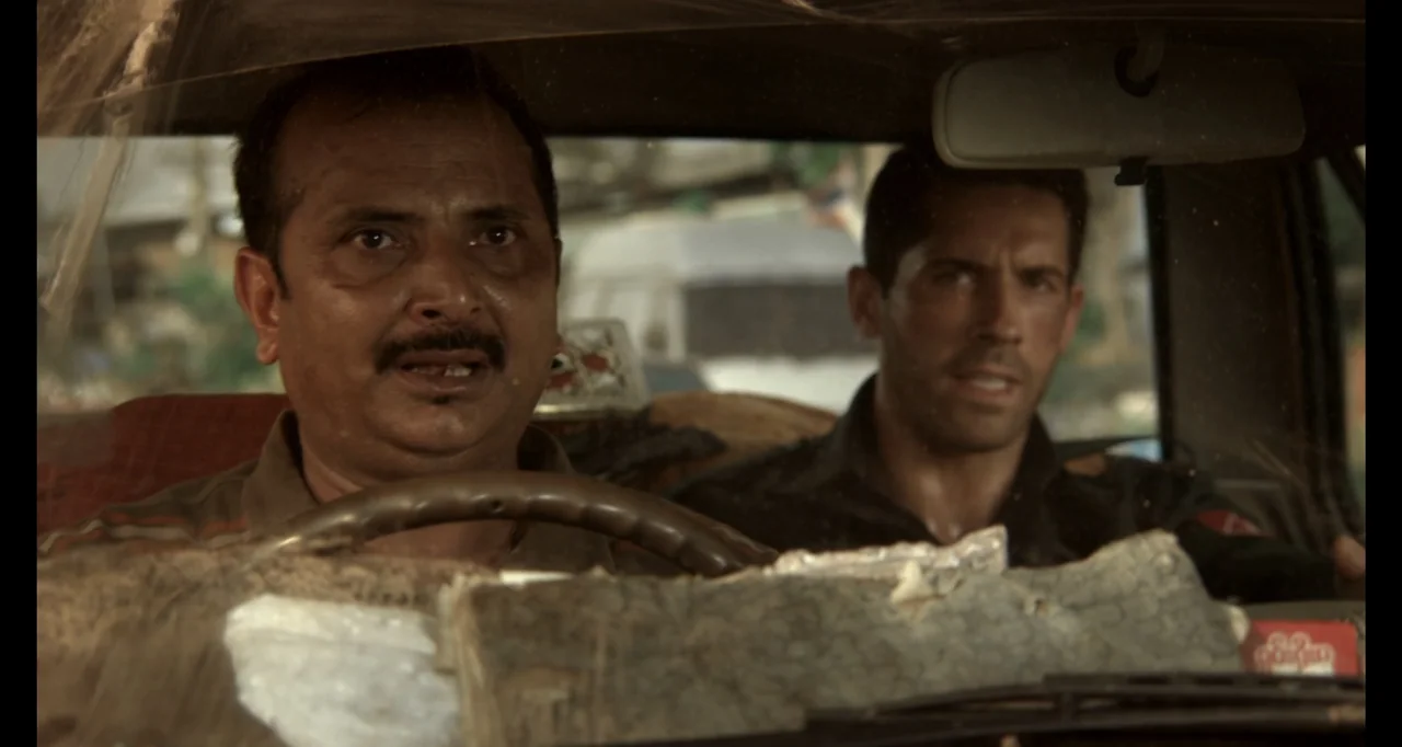 Ninja: Shadow of a Tear (2013) movie still: medium — The interior of a car shows two men seated in the front. The driver looks forward while the…