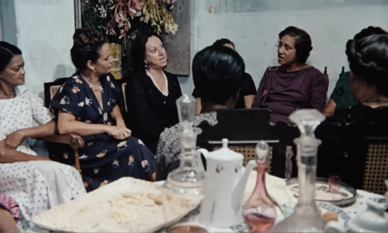 Dona Flor and Her Two Husbands (1976) movie still: medium — A group of five women sits around a table in a dimly lit room. They are talking to each…