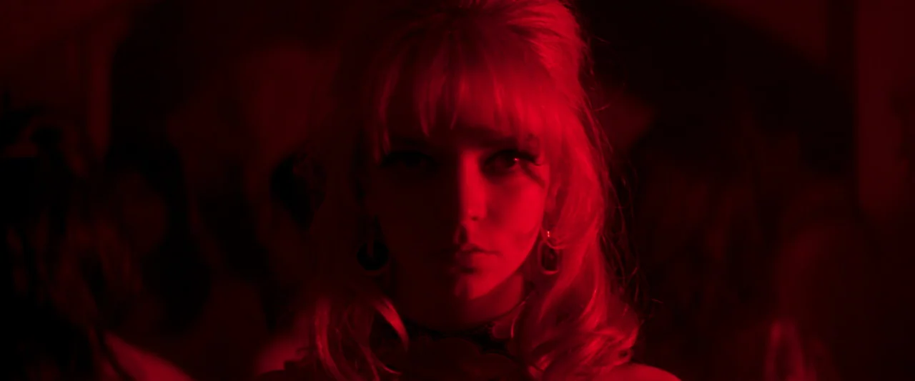 Last Night in Soho (2021) movie still: closeup — A dark environment is illuminated by intense monochromatic red lighting in a nightclub setting. A…