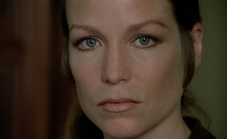 Black Moon (1975) movie still: closeup — An interior space provides a neutral, dimly lit background for a close portrait. A woman stares directly…