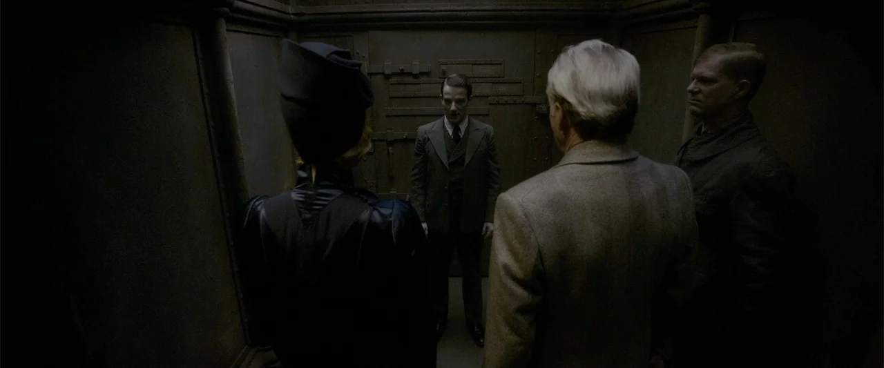 Fantastic Beasts: The Crimes of Grindelwald (2018) movie still: medium — A confined, dark, industrial elevator car has heavy riveted metal wall…