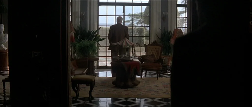 The Prestige (2006) movie still: wide — A formal sunroom features black and white marble floor tiles and tall glass windows. An elderly man stands…